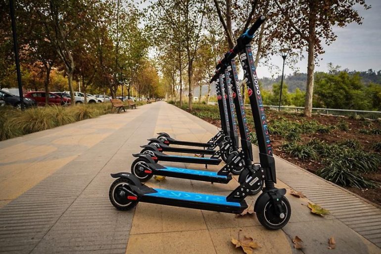 Muestra un grupo de scooters eléctricos en un área peatonal.